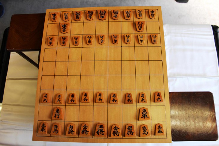 Shogi: A traditional shogi board with a set of shogi pieces in the starting setup. The stands on both sides of the board are used to hold captured pieces. COURTESY OF JAPAN SHOGI ASSOCIATION